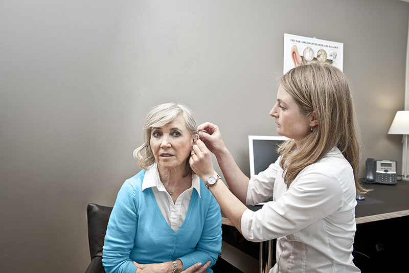 Hearing care specialist fitting a hearing aid